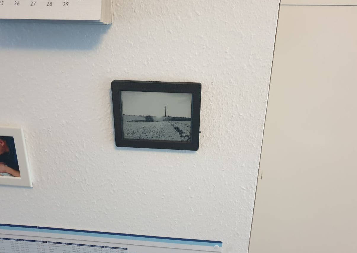 A black picture frame with a black-and-white picture in it hangs on a wall.
